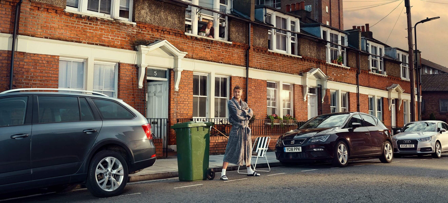 A man reserving a kerbside parking space by standing on it