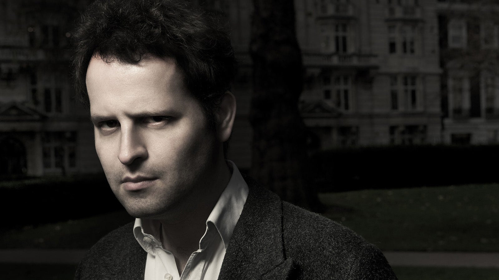 A black and white headshot of Adam Kay