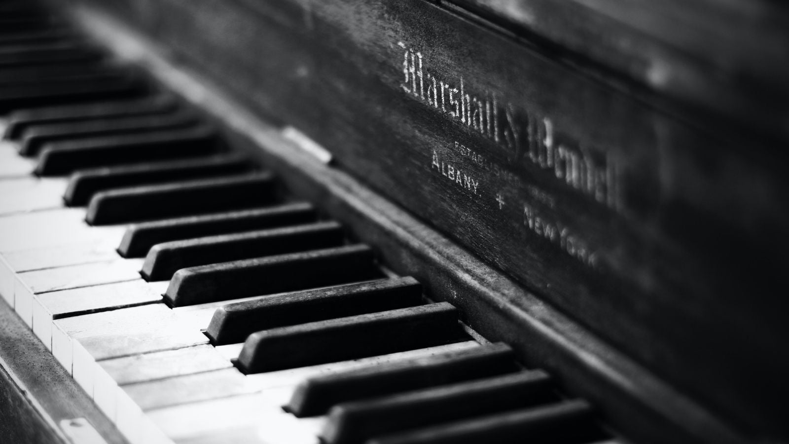 Black and white close up photo of piano keys on a wooden piano