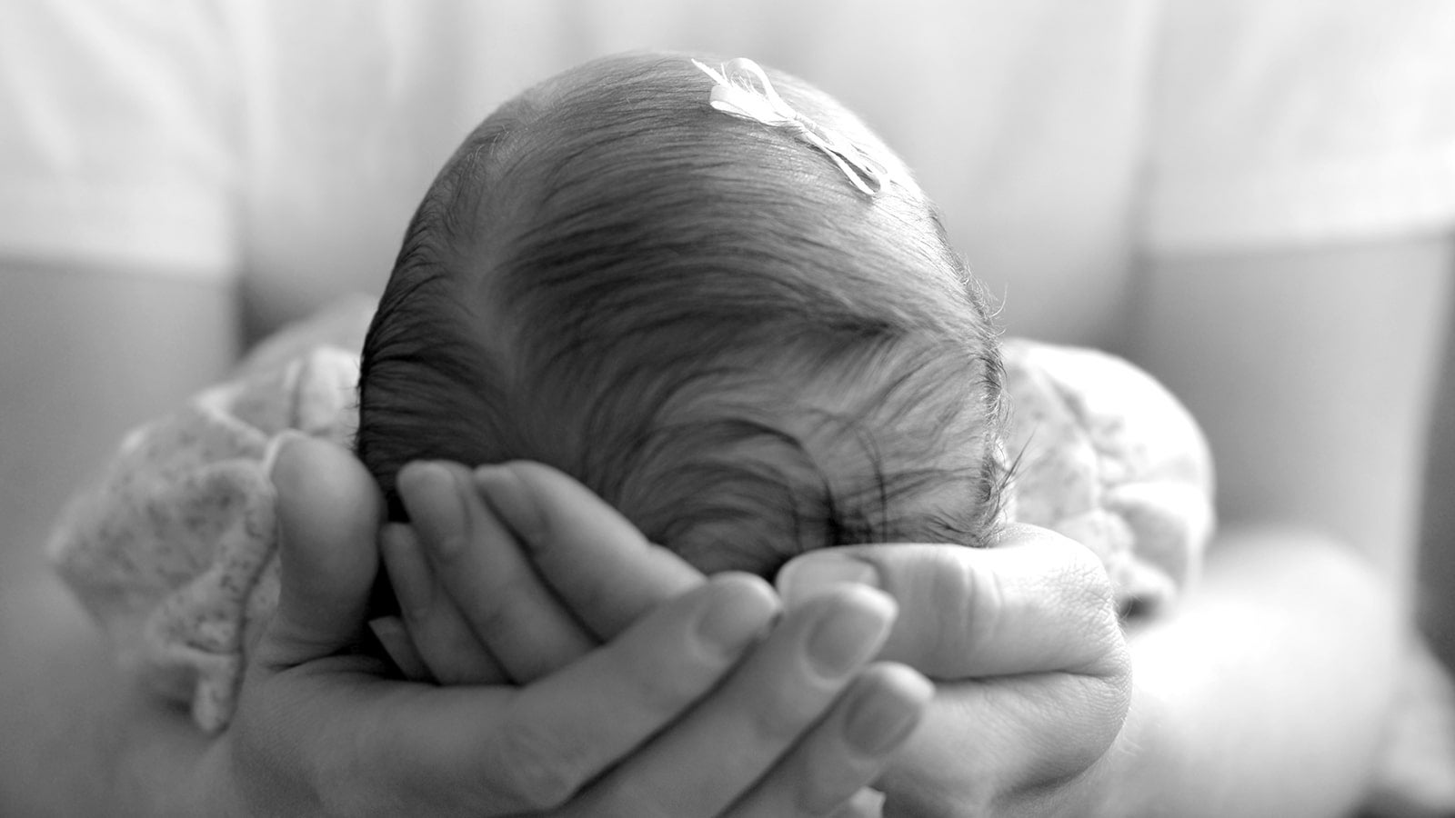 Black and white photo of baby head being cradled in someone's hands