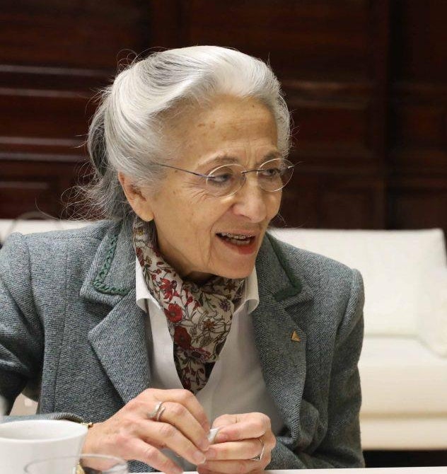 A colour photograph of Rita Levi-Montalcini mid-conversation wearing a grey suit