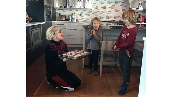 lady Gaga with Elton John and David Furnish's children in the kitchen on her knees with a tray of cupcakes
