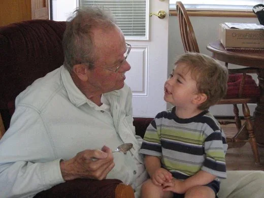 Kent talking with his young Grandson, who is sitting on his knee