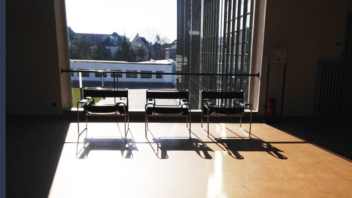 Three kandinsky chairs in front of a window, casting long shadows on the floor