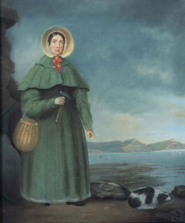 Colour painting of Mary Anning, standing on a beach, holding a small basket and hammer, pointing down to the newly discover fossil of an ammonite