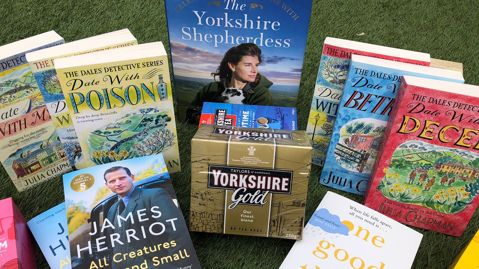 Boxes of Yorkshire Tea and a number of books sit arrange on a patch of grass.