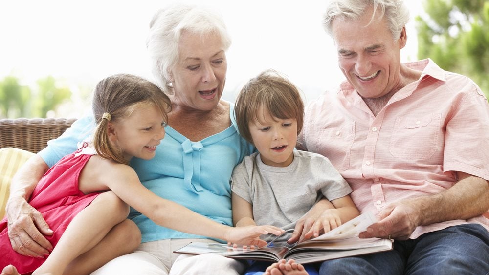 Young boy and girl reading a book with their grandparents