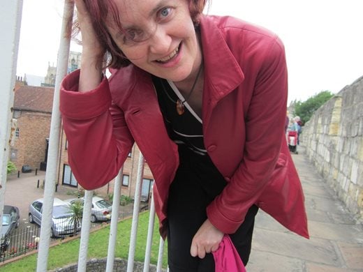 Photo of Emma leaning down and smiling into the camera, wearing a red leather jacket