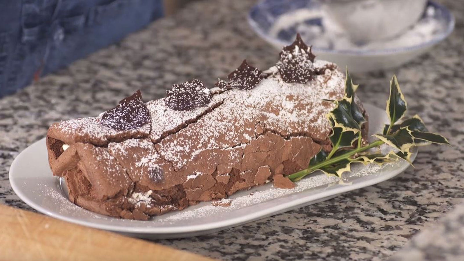 A chocolate Yule Log decorated with chocolate leaves, icing sugar and with ivy leaves.