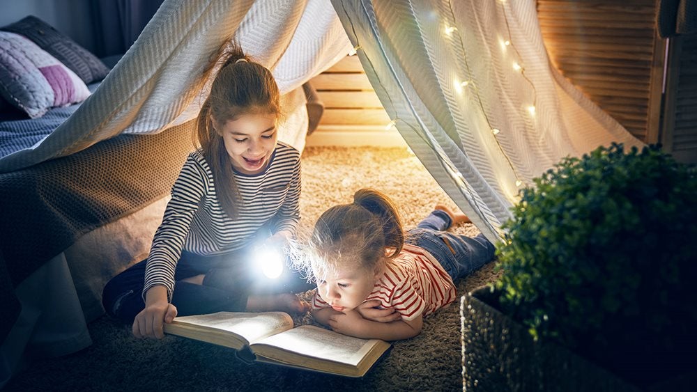 Two girls reading together in an indoor tent