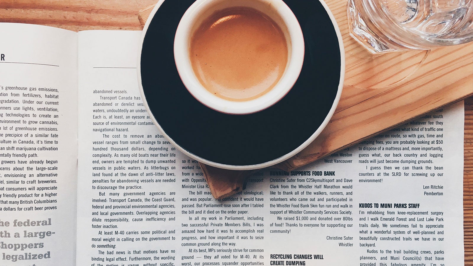 Coffee cup next to an open newspaper