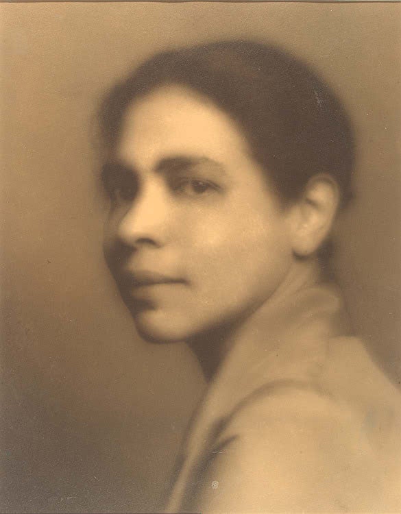 A sepia toned, close-up photograph of Nella Larsen, looking to camera with a slight smile