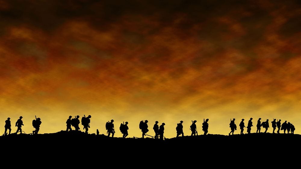 Silhouette of soldiers walking in a line against a yellow ashy background