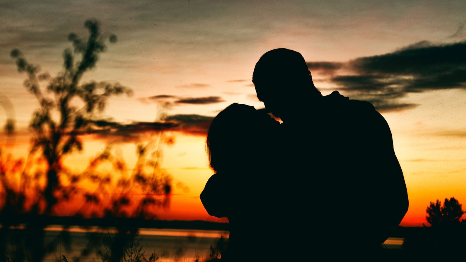 Silhouette of couple about to kiss at sunset 