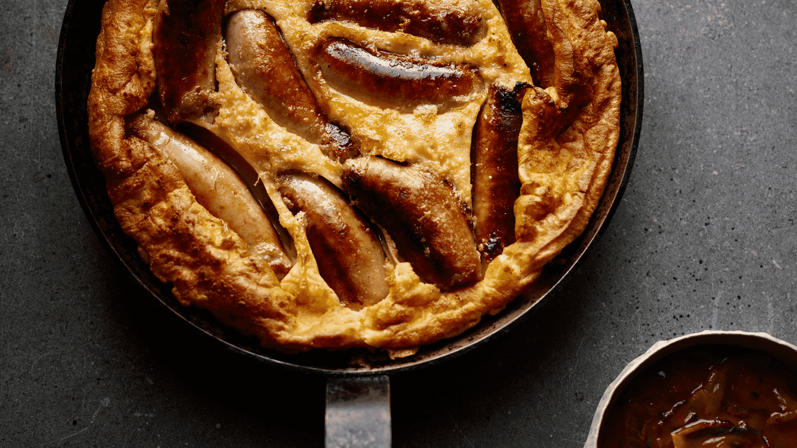 Toad in the hole cooked in a pan, sitting on a concrete worktop