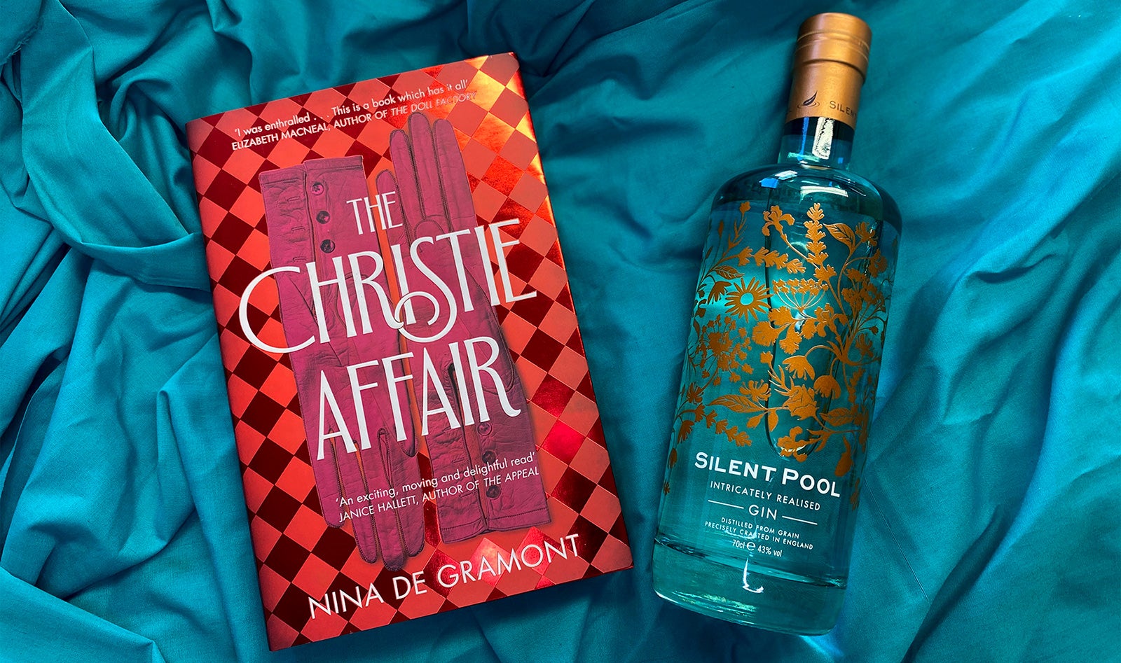 A copy of The Christie Affair and a bottle of Silent Pool gin rest on a blue cloth.