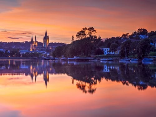 Truro at sunset, with a church lit up in the background and boats moored along the docks