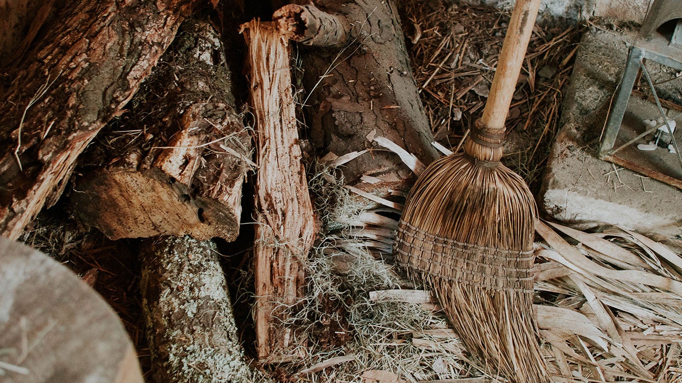 Hand made vintage broom leaning against some logs