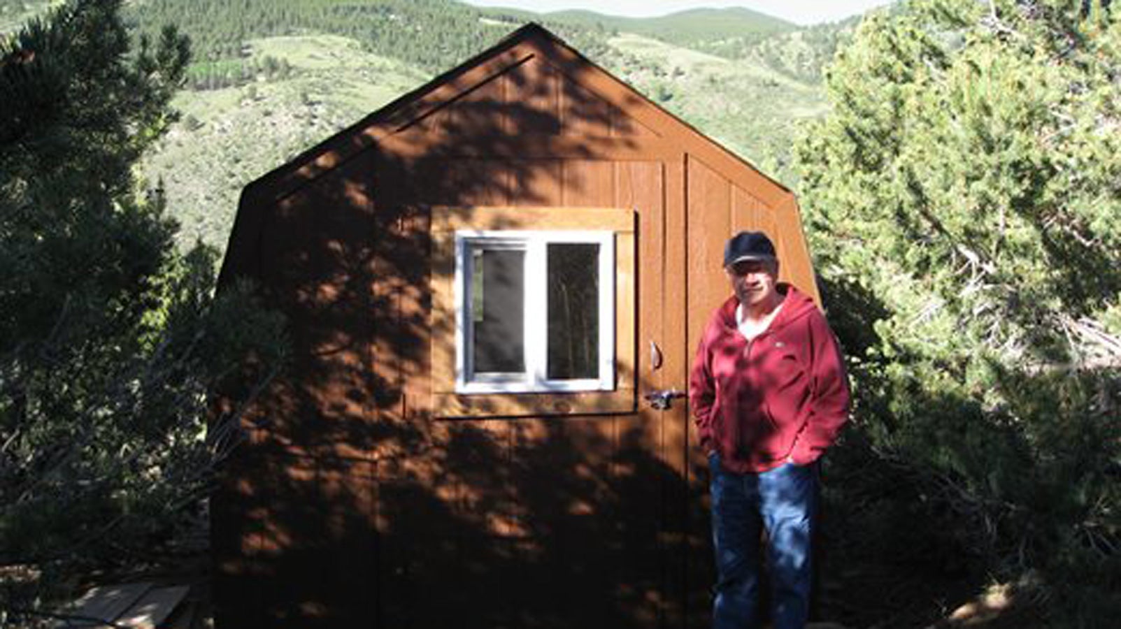 Kent Haruf outside his writing shed, with the mountains of Colorado in the background