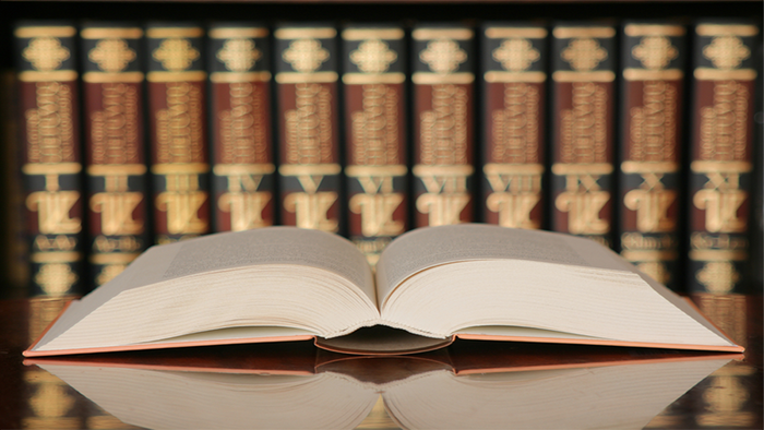 Open book on table with books in the background