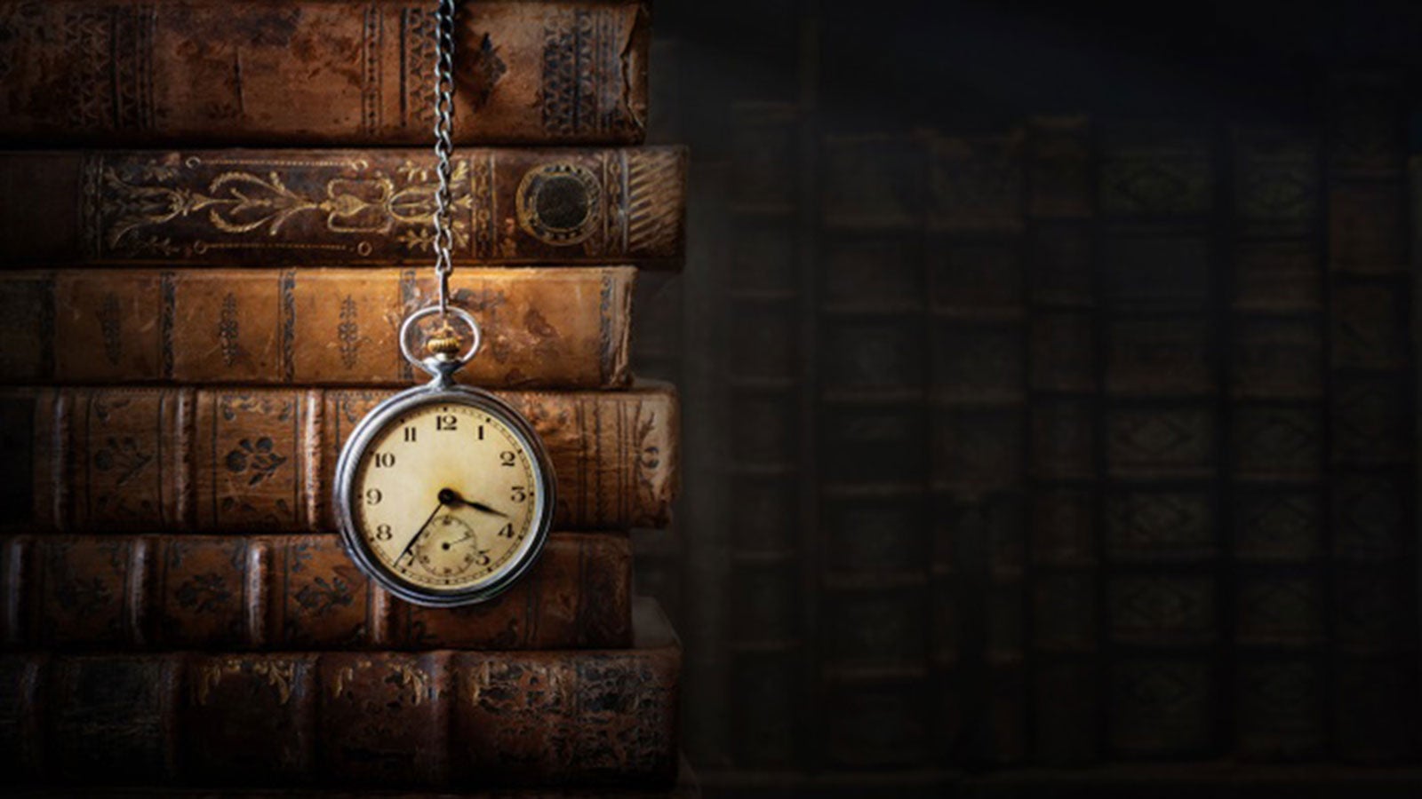 Stack of old books with a pocket watch draped over them