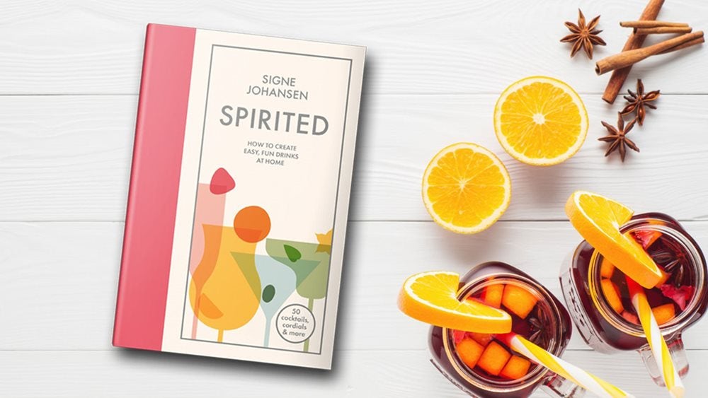 Spirited book next to two glasses of cocktails