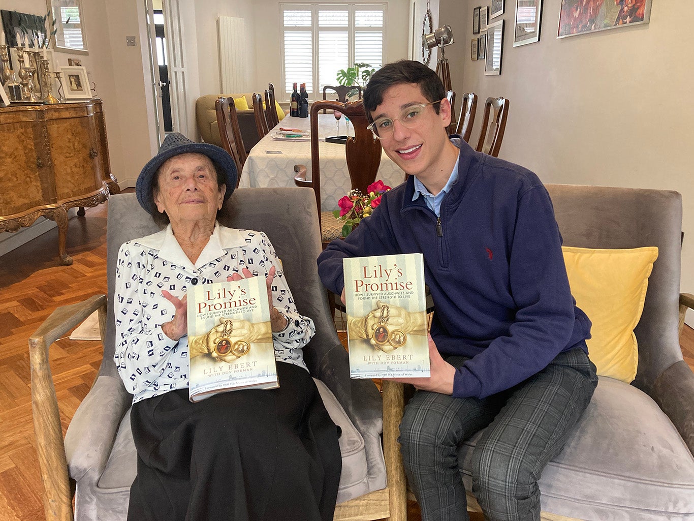Dov Forman sits beside his great-grandmother Lily Ebert, each holding a copy of their book Lily's Promise