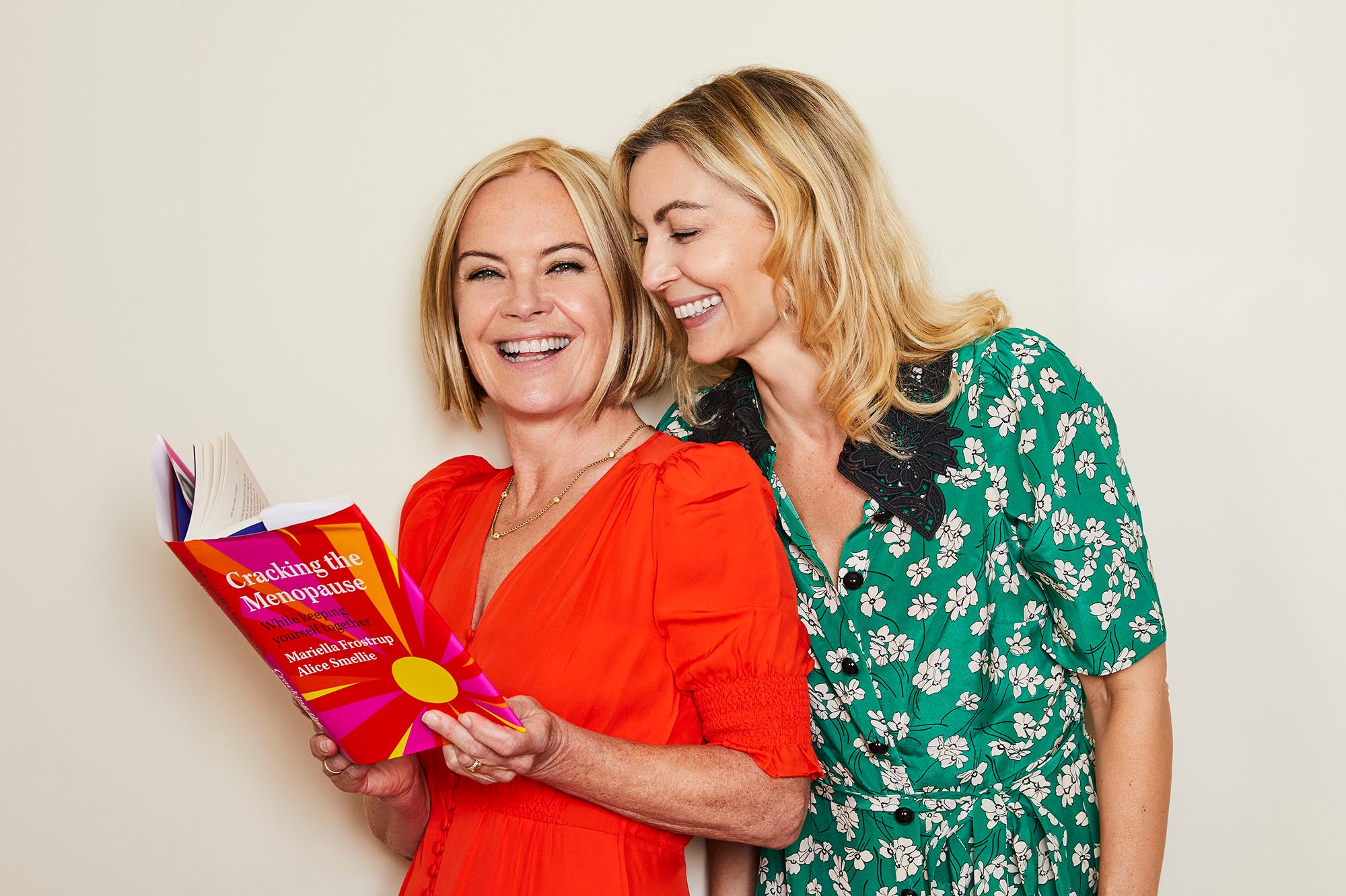 Mariella Frostrup and Alice Smellie laughing together holding their book Cracking the Menopause