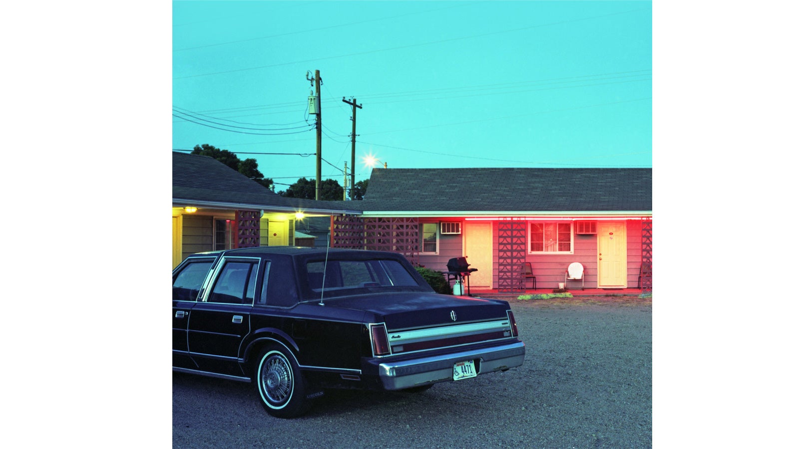 A vintage car in front of a motel at dusk