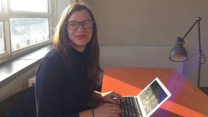 Naomi Wood sitting at an orange Ikea desk with a grey anglepoise lamp in one of the student's rooms at the Bauhaus. 