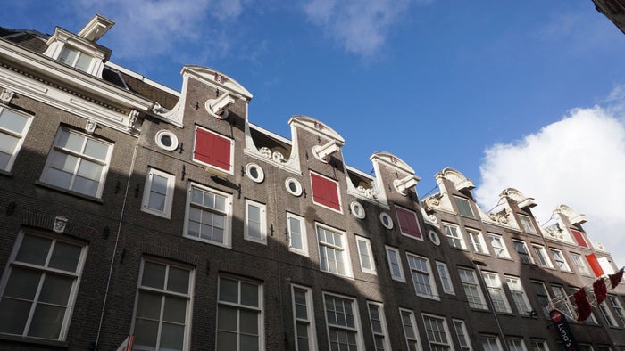 The tall houses above the shops of Kalverstraat with a blue sky above