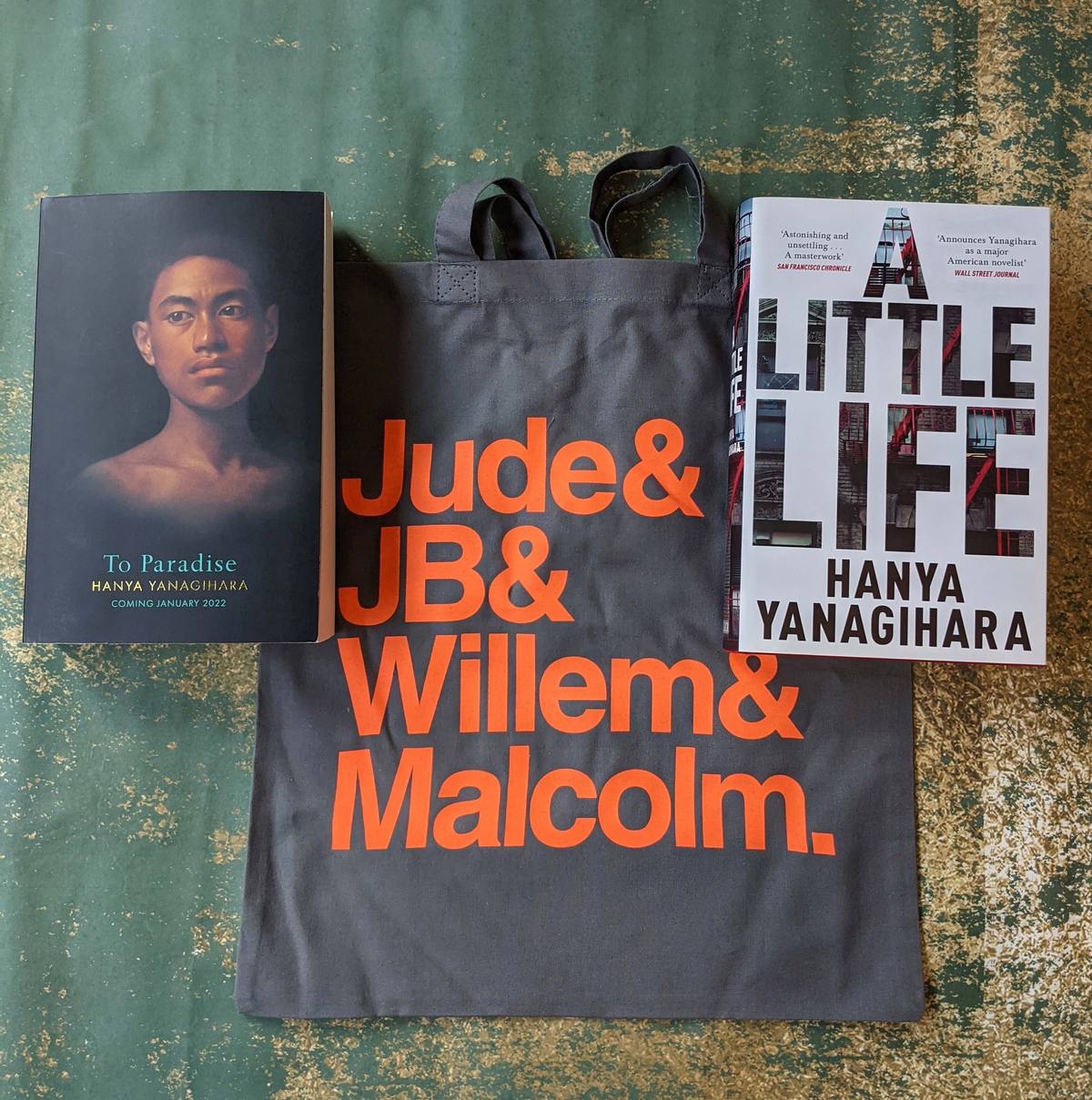 A copy of A Little Life, the exclusive To Paradise proof and a tote bag arranged on a table.