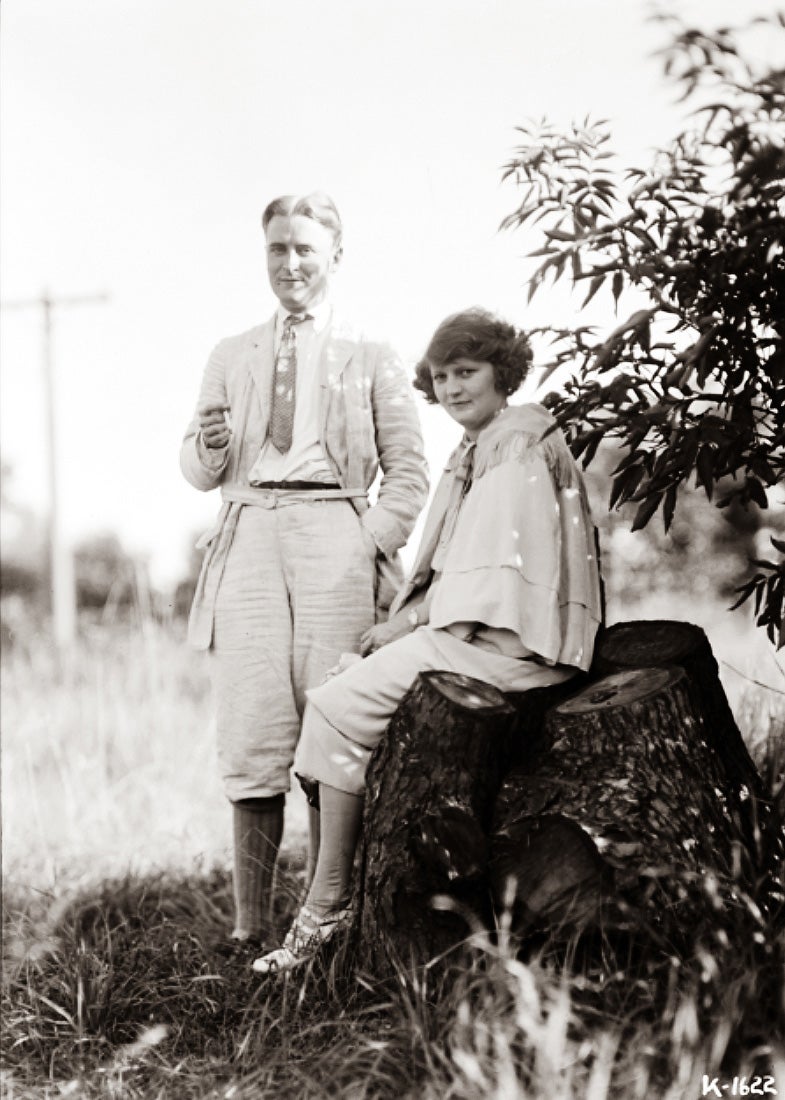 F. Scott Fitzerald and his wife Zelda sit on a tree stump in an open field at Dellwood