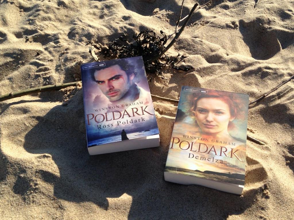 A picture of the books Ross Poldark and Demelza on the sand