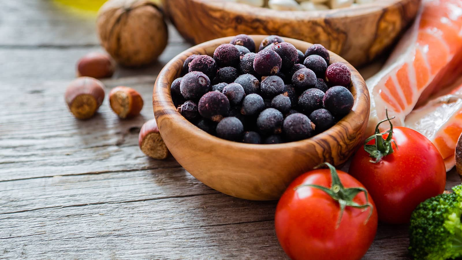 Wooden bowl of blueberries with arrangement of other healthy food - tomatoes