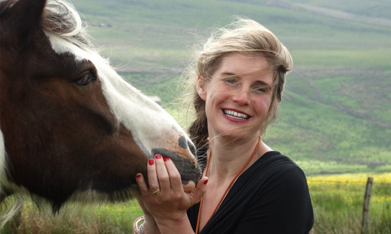The Yorkshire Shepherdess, Amanda Owen, with a horse in a field.