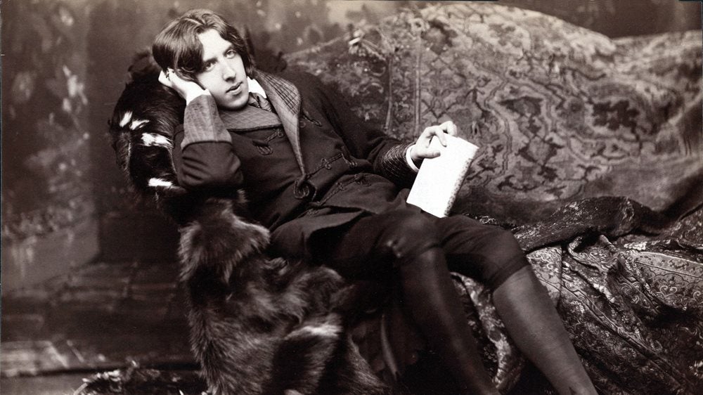 Oscar Wilde photographed sitting in a fur covered chair. 