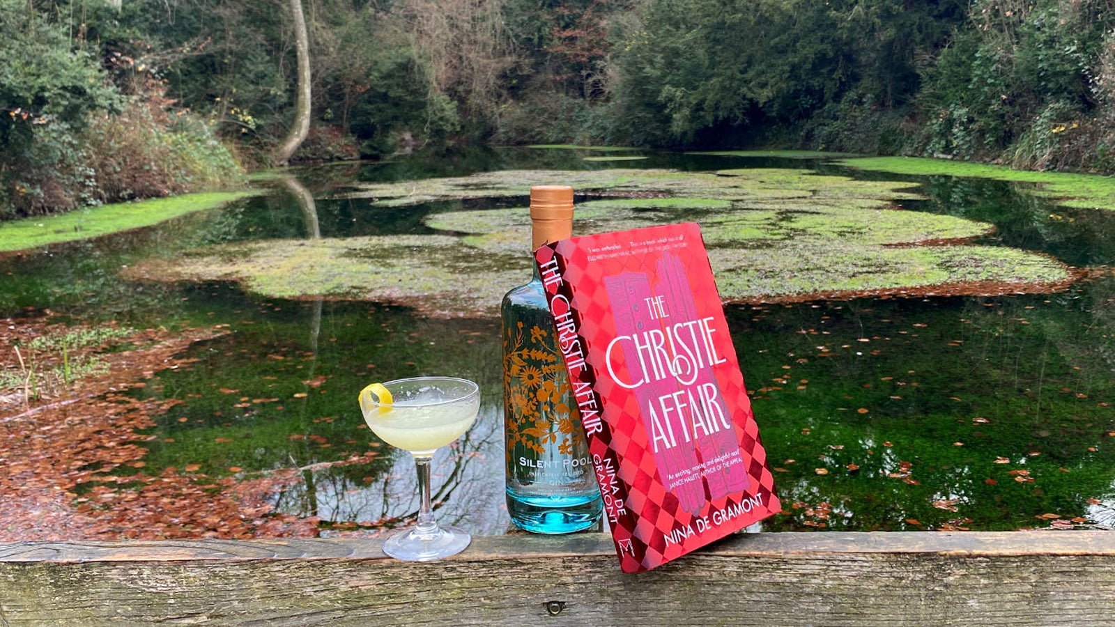 A cocktail, a bottle of Silent Pool Gin, and a copy of The Christie Affair