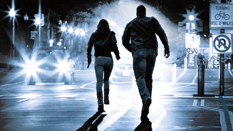 Man and woman running away down street
