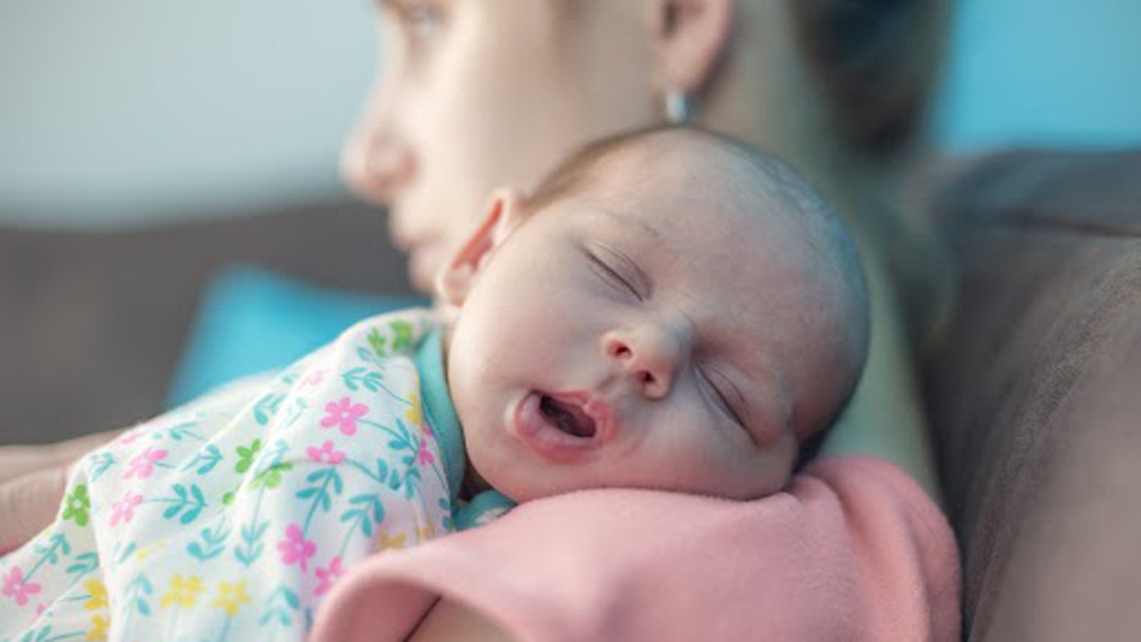 A newborn baby sleeping on a caregiver's shoulder