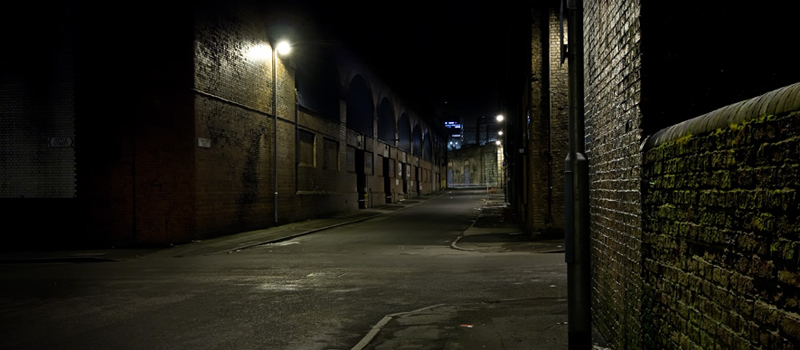 Dark alleyway with light at end and brick walls