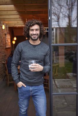 A photo of Joe Wicks holding a glass