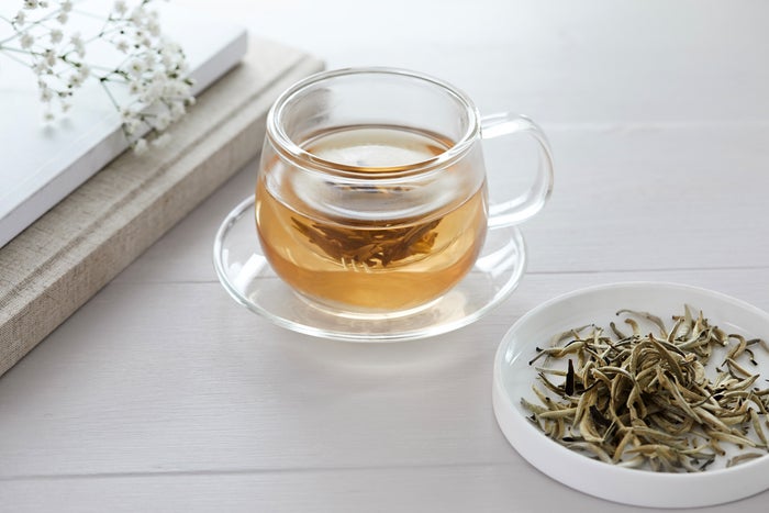 A glass cup of loose leaf tea next to white books