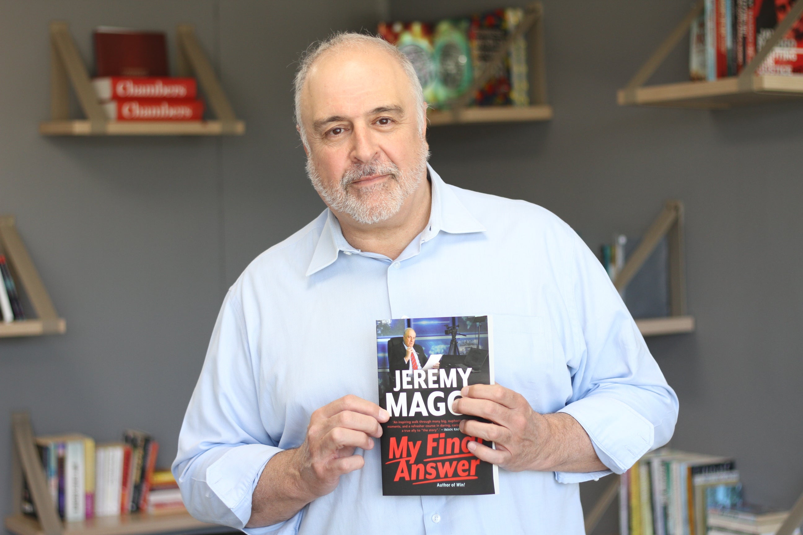 A photo of Jeremy Maggs in a blue shirt, holding a copy of his book 'Final Answer'