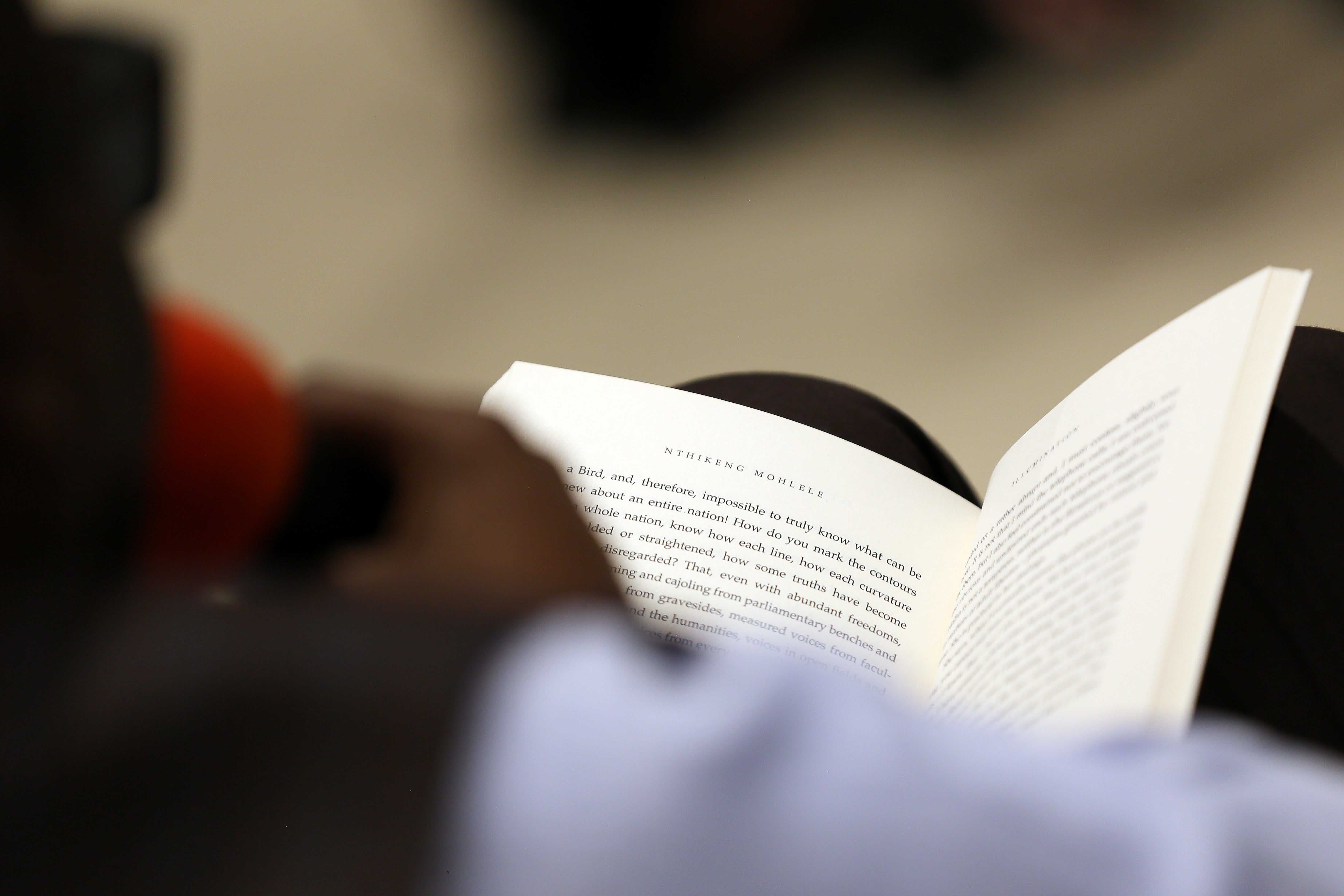 A photo taken over the person's shoulder of them reading a book