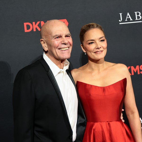 Peter Harf and Katharina Harf pose together on a red carpet in front of a black backdrop with DKMS and JAB logos. Peter Harf wears a black tuxedo, and Katharina Harf wears a strapless red gown. Both are smiling. Peter Harf and Katharina Harf pose together on a red carpet in front of a black backdrop with DKMS and JAB logos. Peter Harf wears a black tuxedo, and Katharina Harf wears a strapless red gown. Both are smiling.