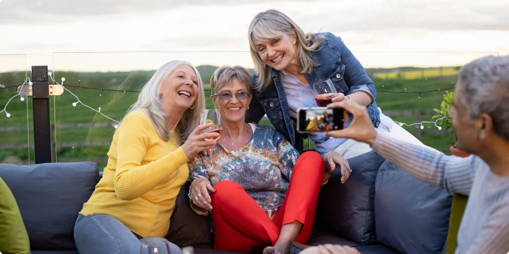 3 friends pose for a photo while enjoying glasses of wine.