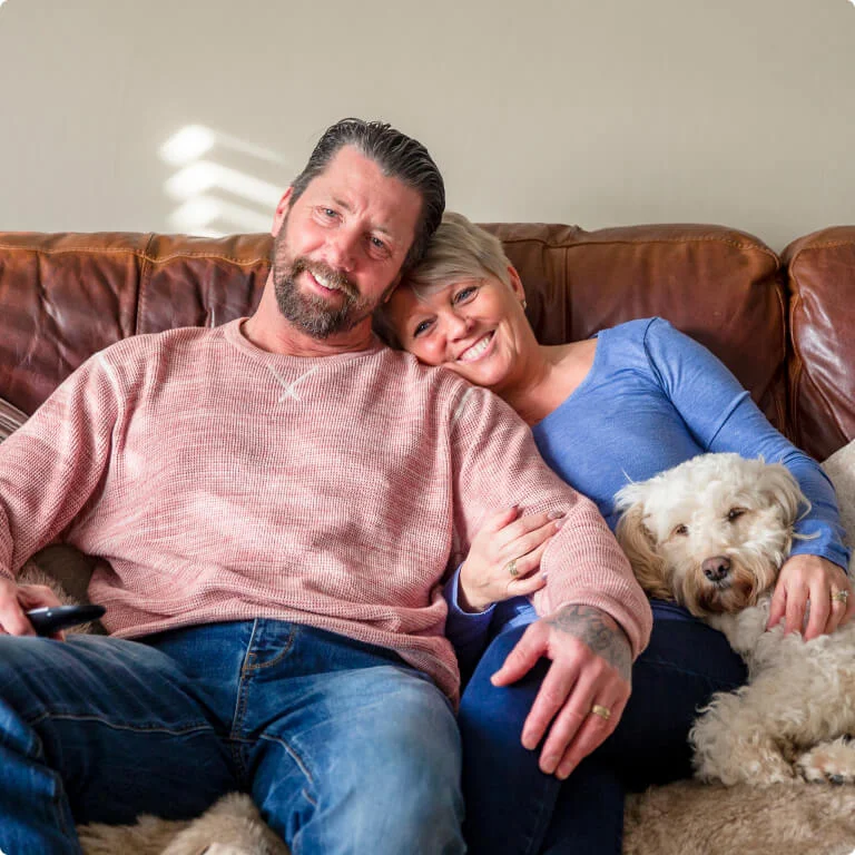 Couple sitting on a couch with their dog. 