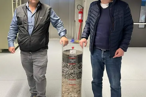 Landesrat Massimo Bessone mit Volkmar Mair, Direktor des Amtes für Geologie und Baustoffprüfung mit einem Zylinder voller Baustoffe für Straßenbau. (Foto: LPA)