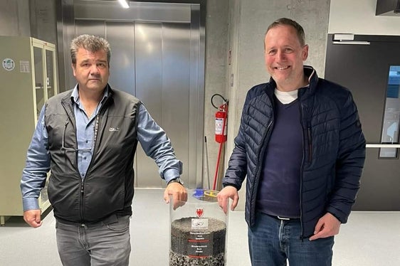 Landesrat Massimo Bessone mit Volkmar Mair, Direktor des Amtes für Geologie und Baustoffprüfung mit einem Zylinder voller Baustoffe für Straßenbau. (Foto: LPA)